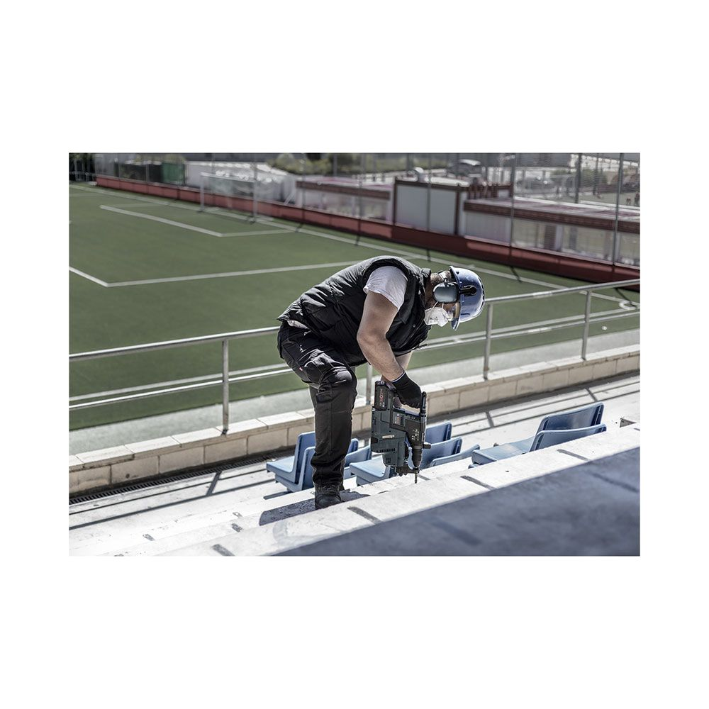 Mężczyzna z wiertarką pracuje na trybunach stadionu.