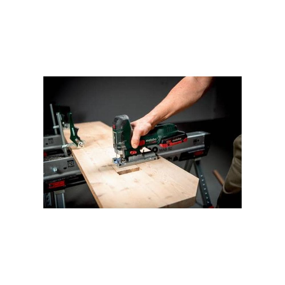 Osoba używa wyrzynarki do cięcia drewna na stole warsztatowym.