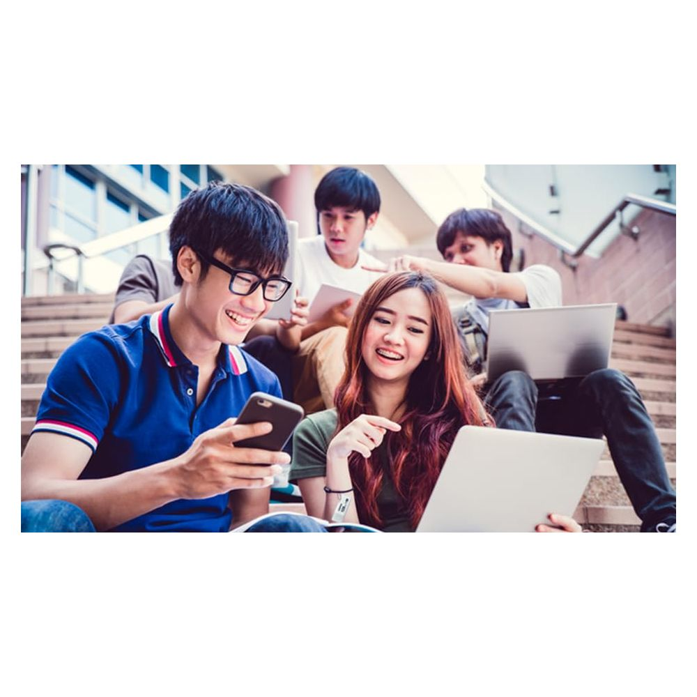 Pięciu młodych ludzi siedzi na schodach, używając laptopów i telefonów.