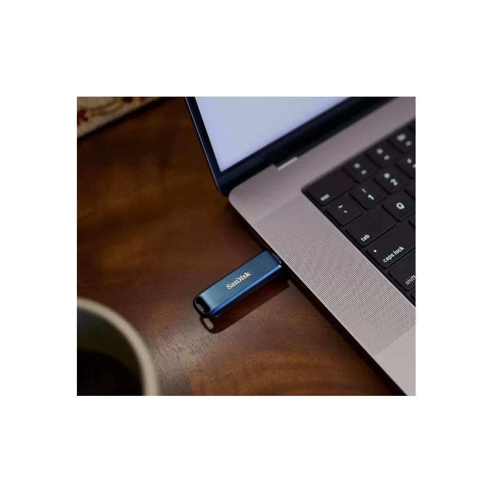 Une clé USB bleue est branchée à un ordinateur portable à côté d'une tasse de café.