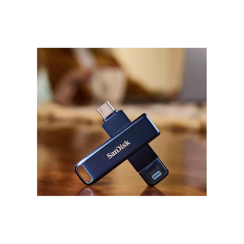 Clé USB SanDisk double connecteur bleu foncé, croisée sur une table en bois.