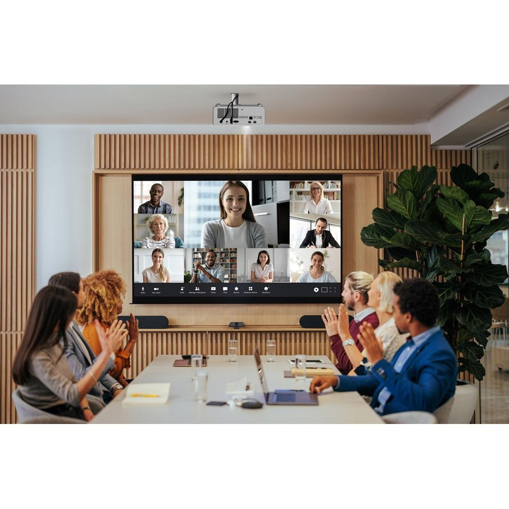 Des gens dans une salle de réunion participent à un appel vidéo sur grand écran.