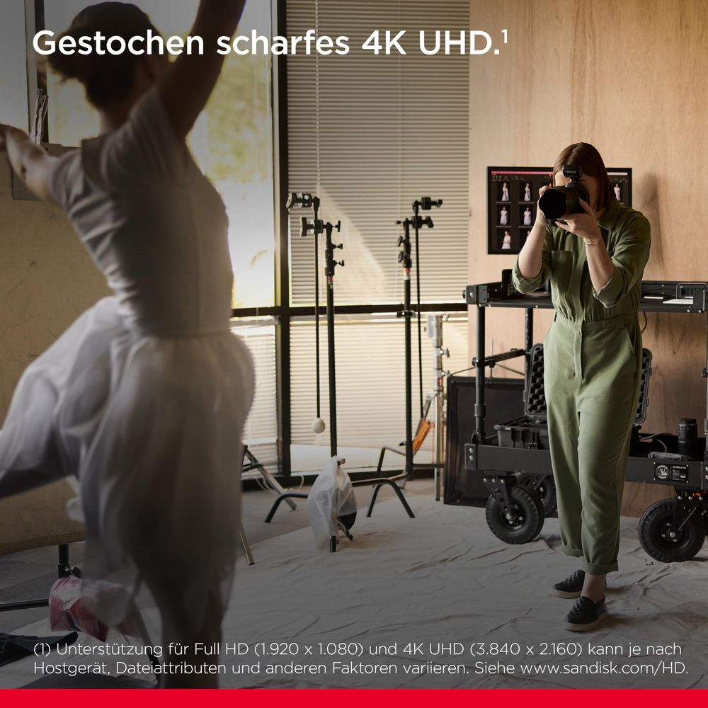 Eine Tänzerin in Weiß wird von einer Frau mit Kamera in einem Studio mit Beleuchtung gefilmt.