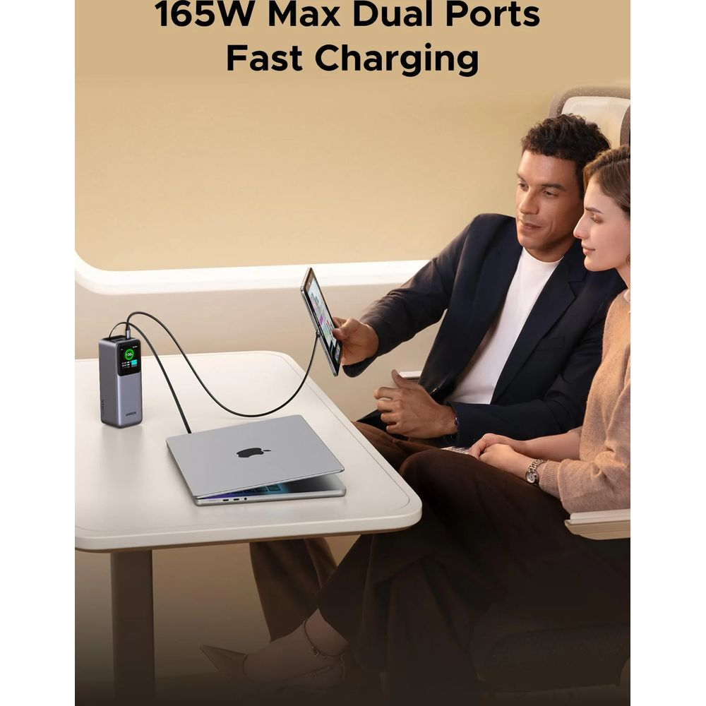 Mężczyzna i kobieta siedzą przy stole. Ładowarka zasila laptopa i tablet.