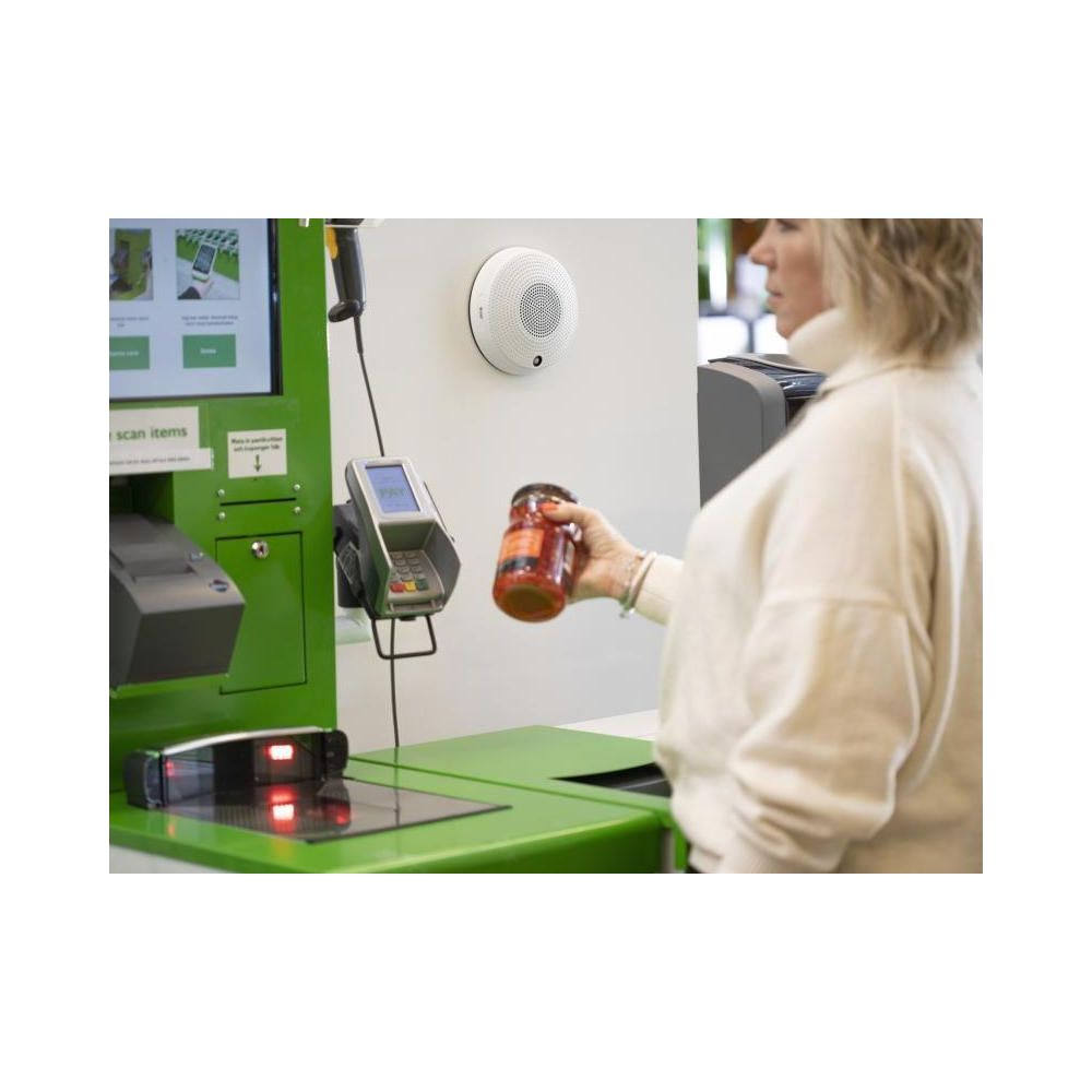 Eine Frau hält ein Glas vor einem Kassenscanner in einem Geschäft.