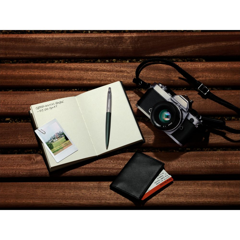 Taccuino, penna, macchina fotografica, portafoglio e foto su superficie in legno.