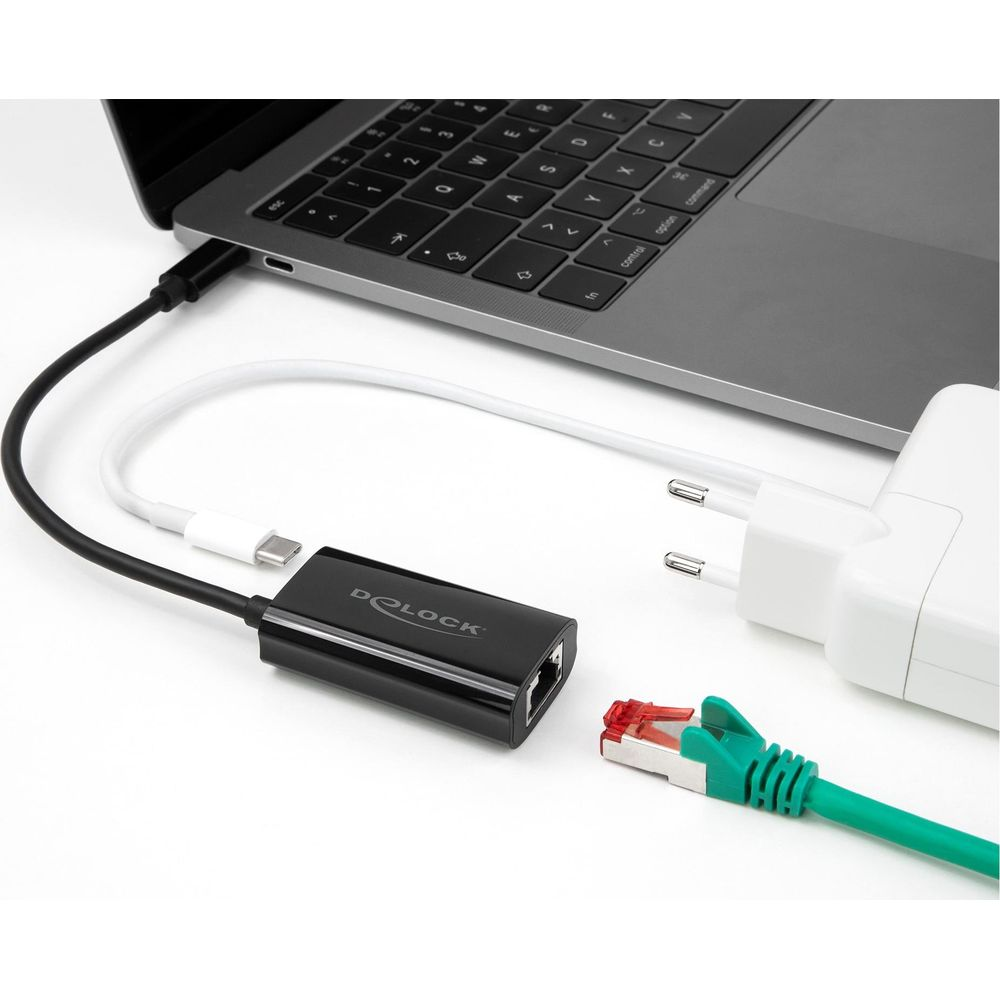 Un adaptador Delock negro, cable USB-C blanco y adaptador de corriente a un portátil.