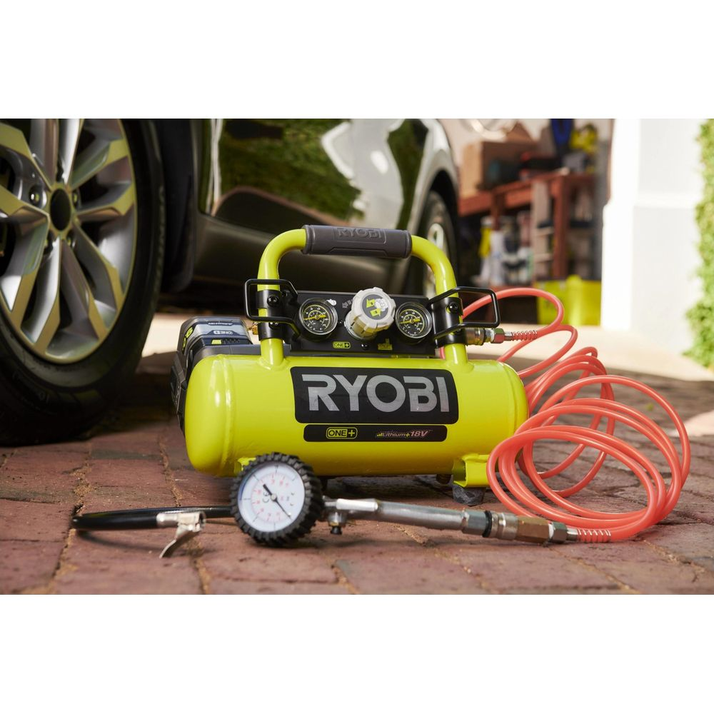 Un compressore d'aria Ryobi giallo con tubo e gonfiatore su mattoni.