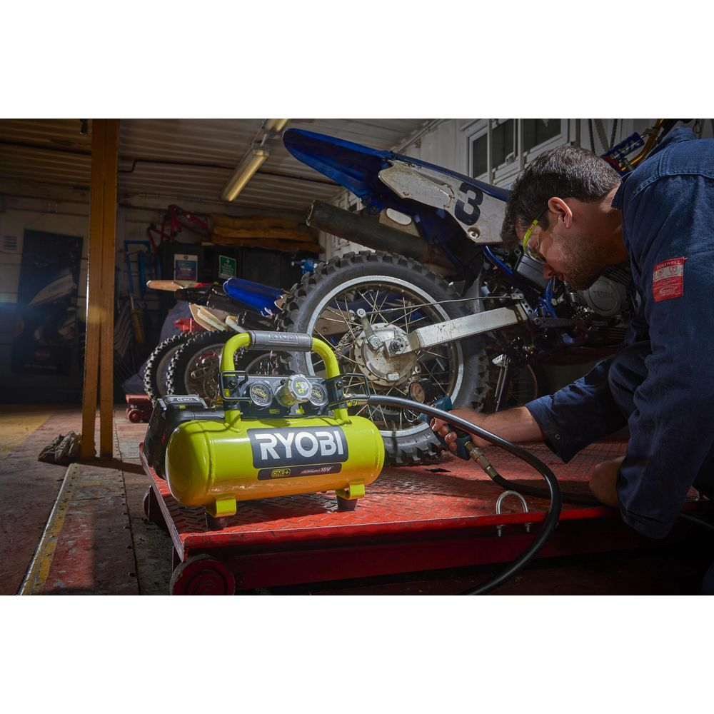 Uomo in officina usa compressore su pneumatico moto.