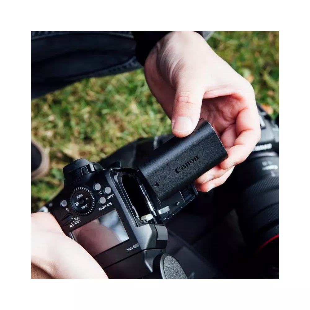 Una mano inserta una batería Canon en una cámara.