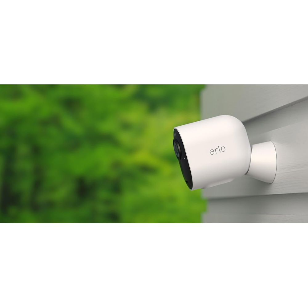 Biała kamera Arlo na szarej elewacji, zielone tło.