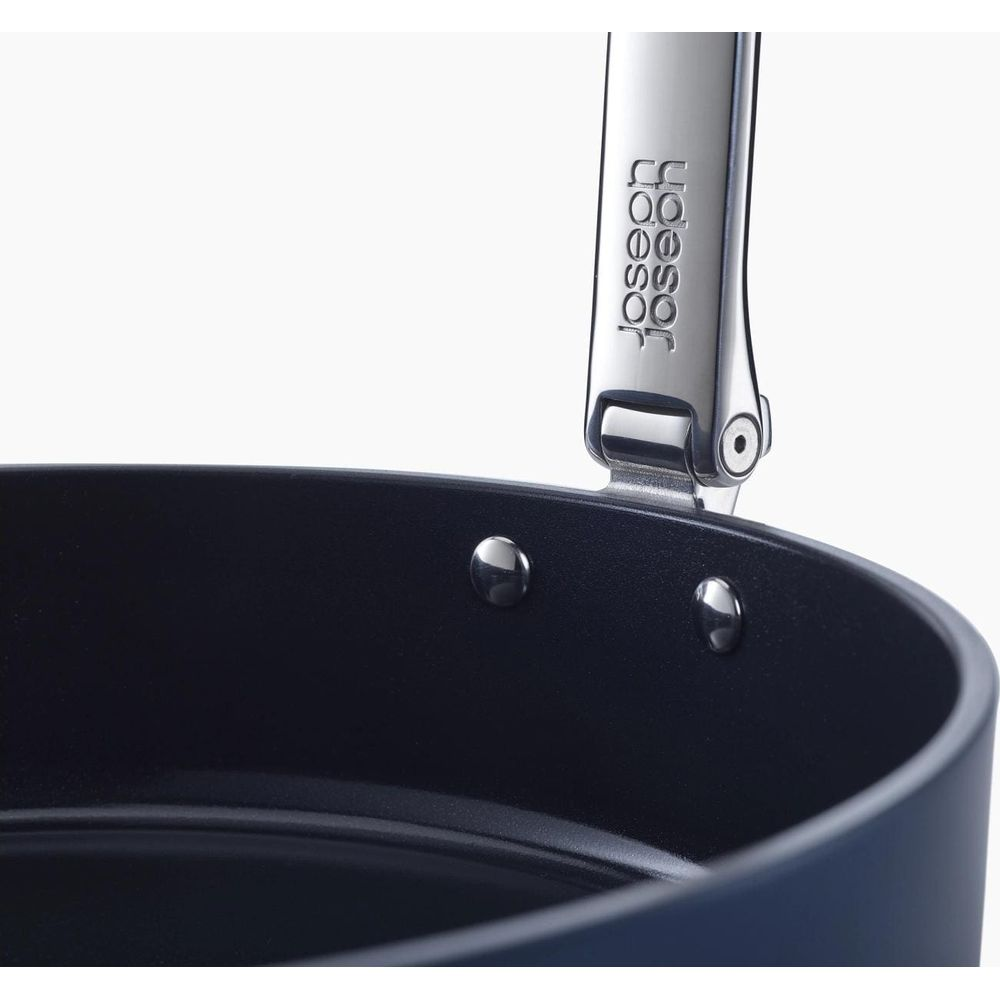 Primer plano de una olla azul oscuro con mango plateado. El mango tiene el logo de Joseph Joseph.