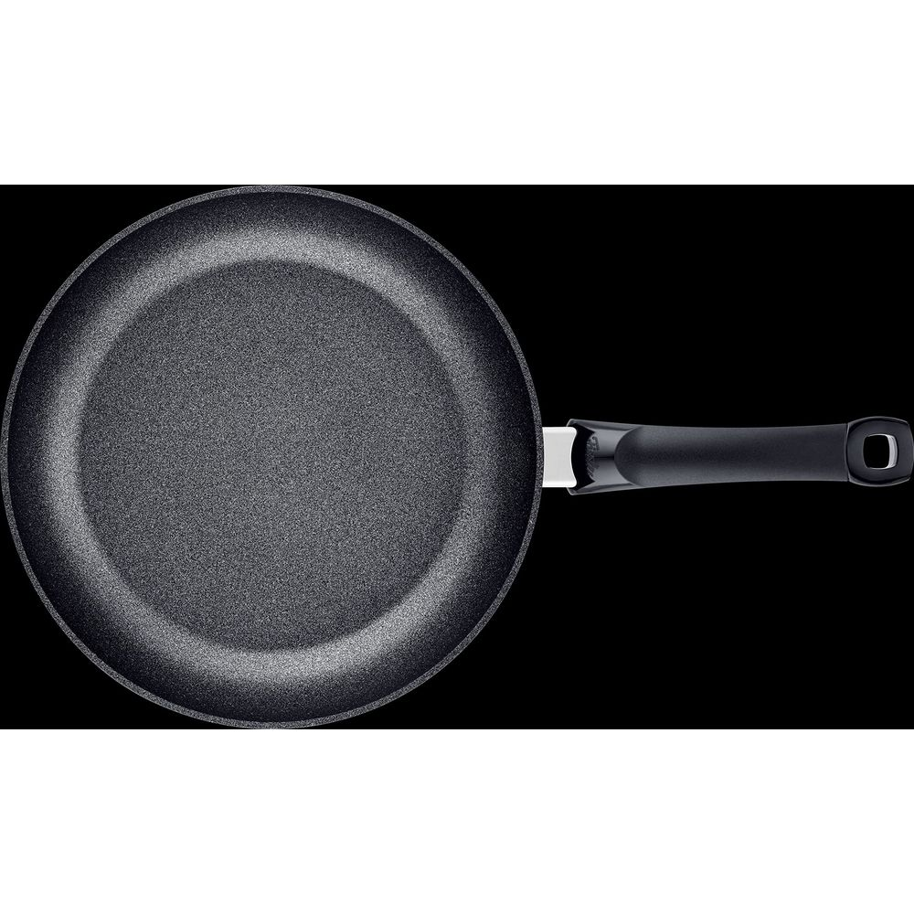 Una padella grigia con manico nero su sfondo nero.