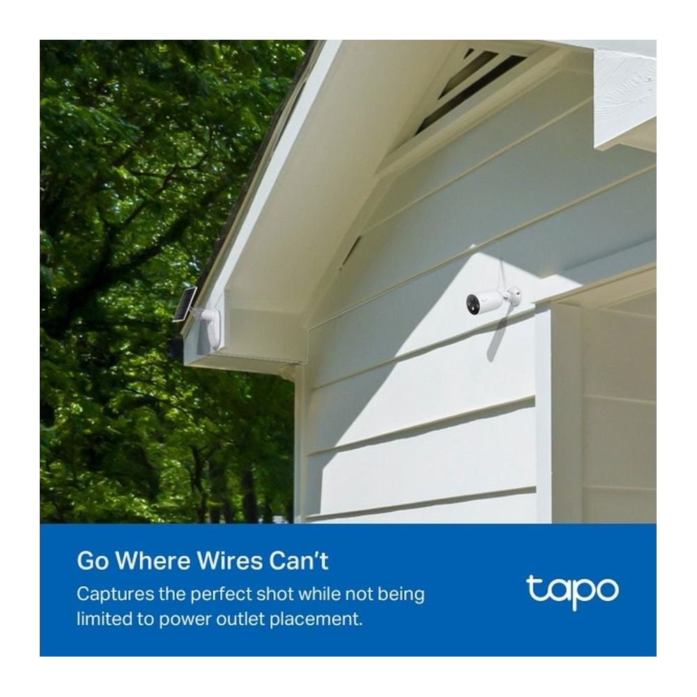 Biała kamera bezpieczeństwa z panelem słonecznym na domu, pod drzewami.