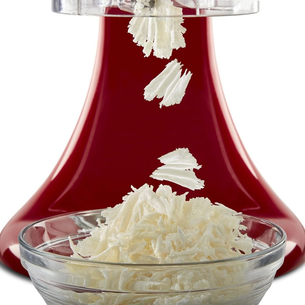 Ein roter Mixer zerkleinert Käse in eine Schüssel.