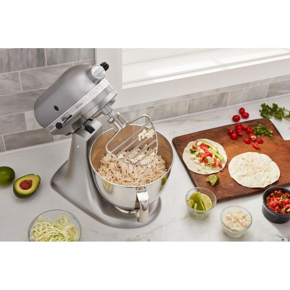 Silberner Küchenmixer bereitet Hühnchen zu, daneben Tortillas und Zutaten für Tacos.