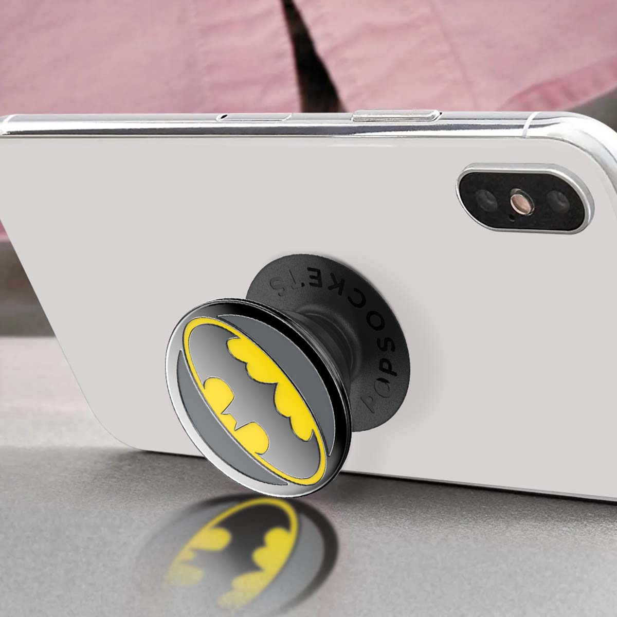 Un soporte negro para teléfono con el logo de Batman en un smartphone blanco.