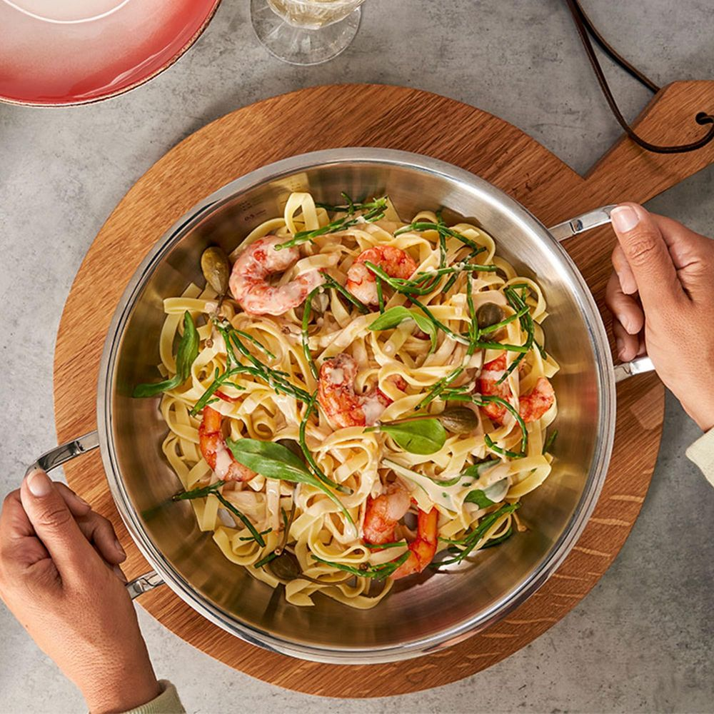 Pasta fettuccine con gamberi, erbe e capperi in salsa cremosa.