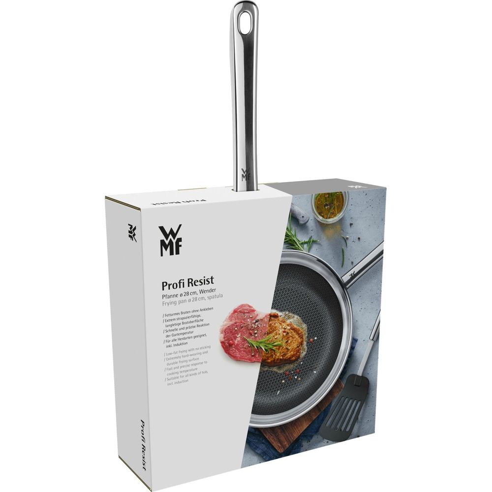 Patelnia z rączką i mięsem na powierzchni, obok łopatka.