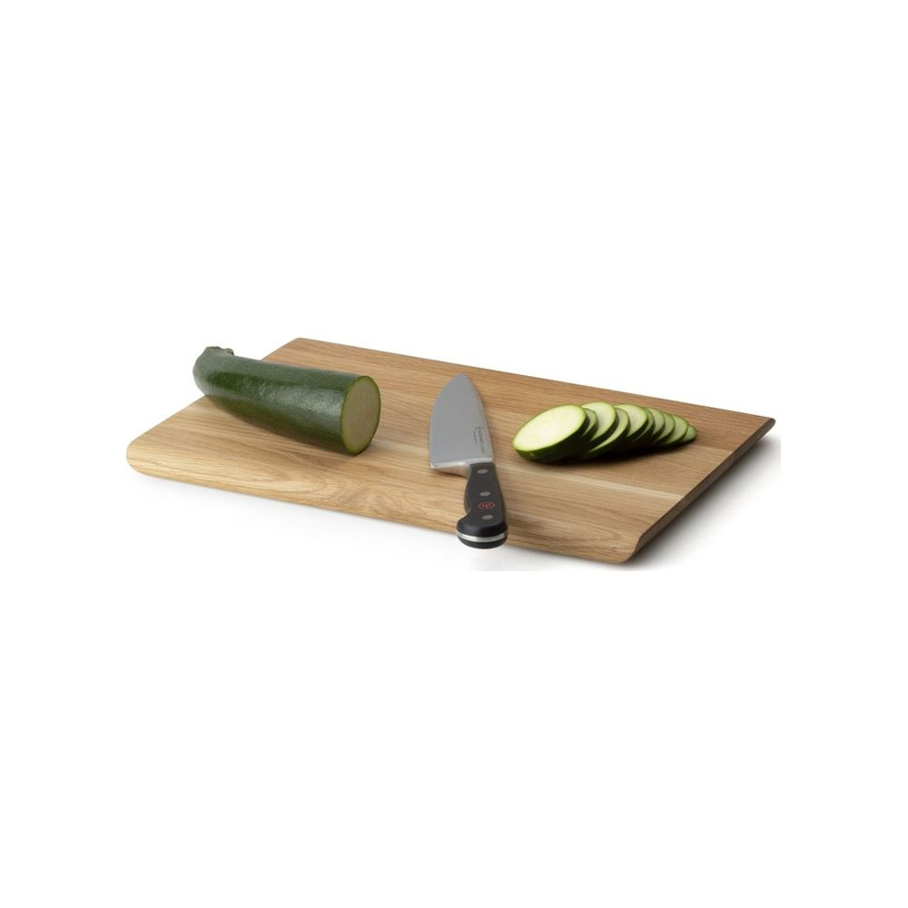 Ein Kochmesser liegt auf einem Holzbrett neben einem angeschnittenen Zucchini und Scheiben.
