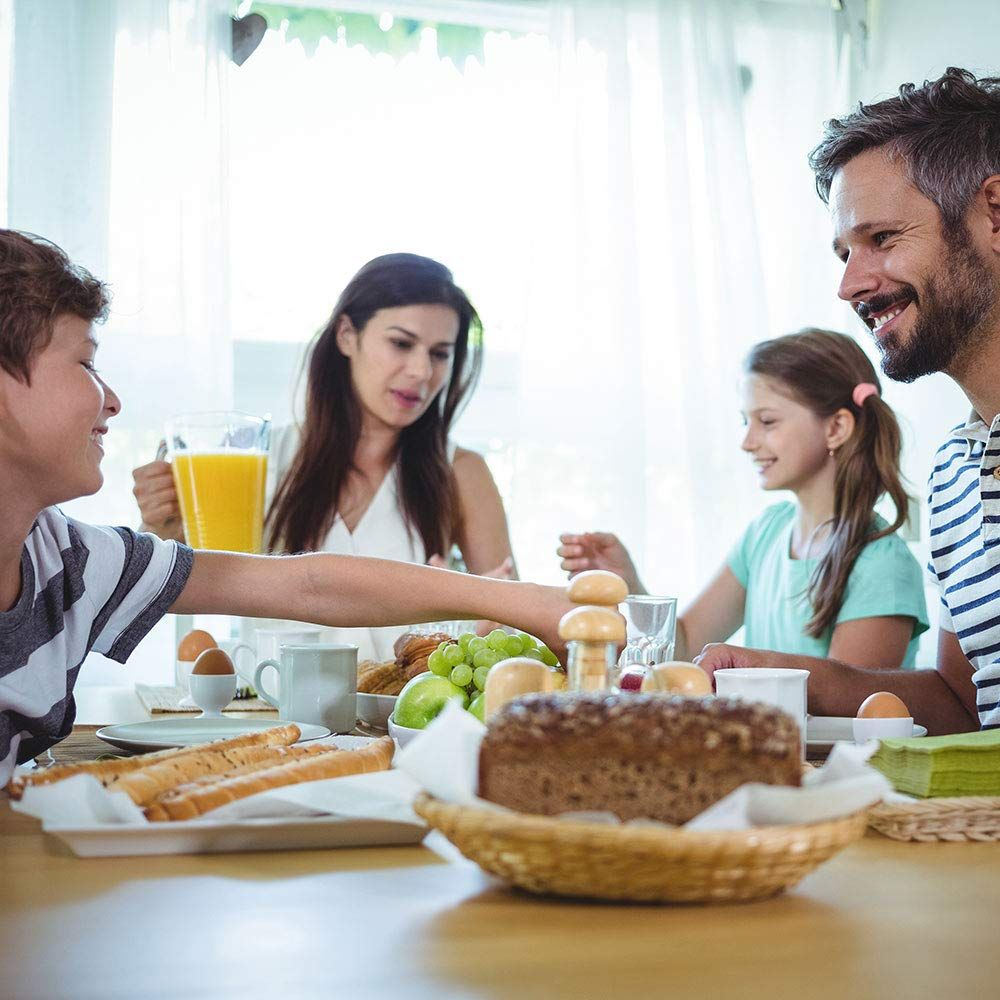 Familie beim Frühstück mit Brot, Obst, Eiern und Saft.