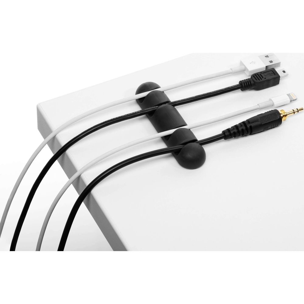 Schwarze und weiße Kabel, organisiert durch schwarze Clips auf weißer Oberfläche.