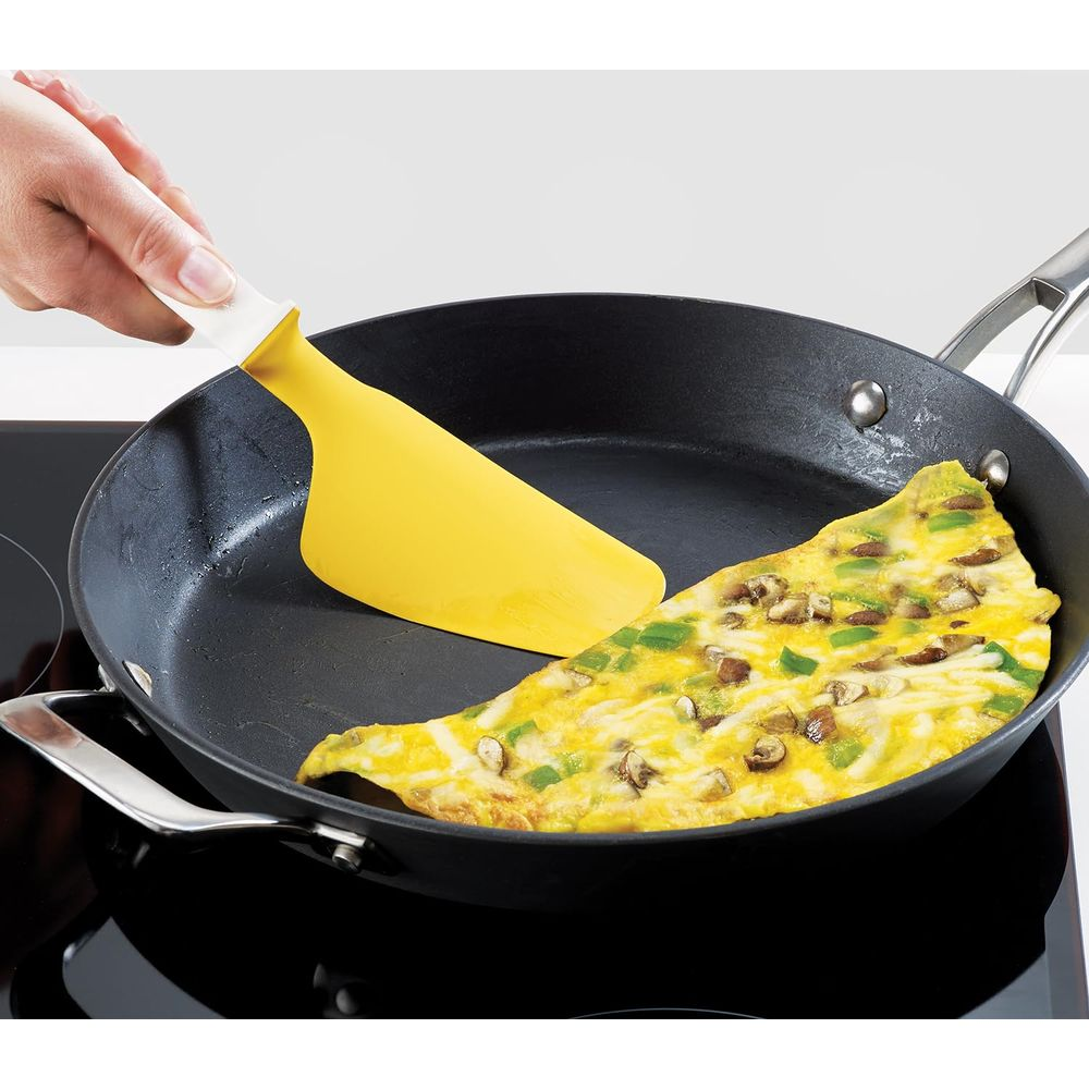 Sarı bir spatula tavada mantarlı ve biberli omleti kaldırıyor.