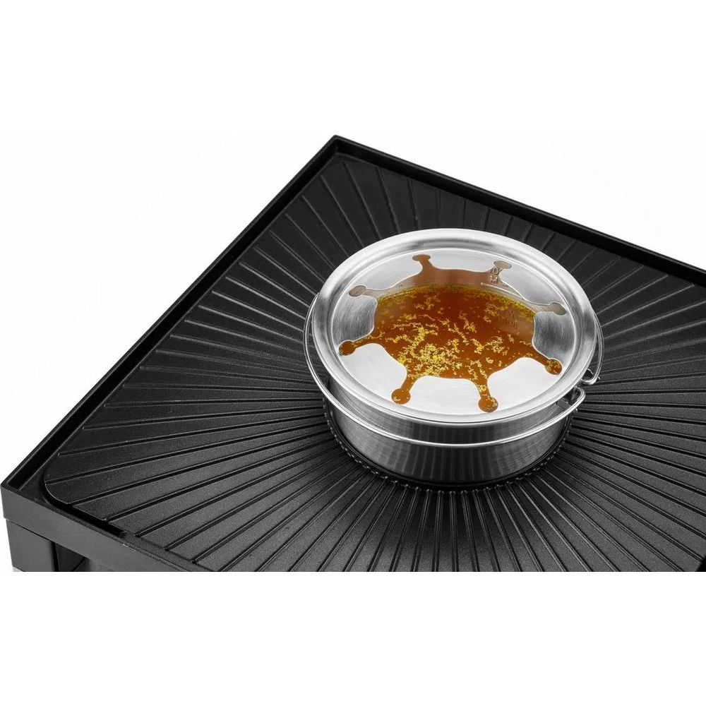 Srebrny pojemnik z brązowym płynem stoi na czarnym grillu.