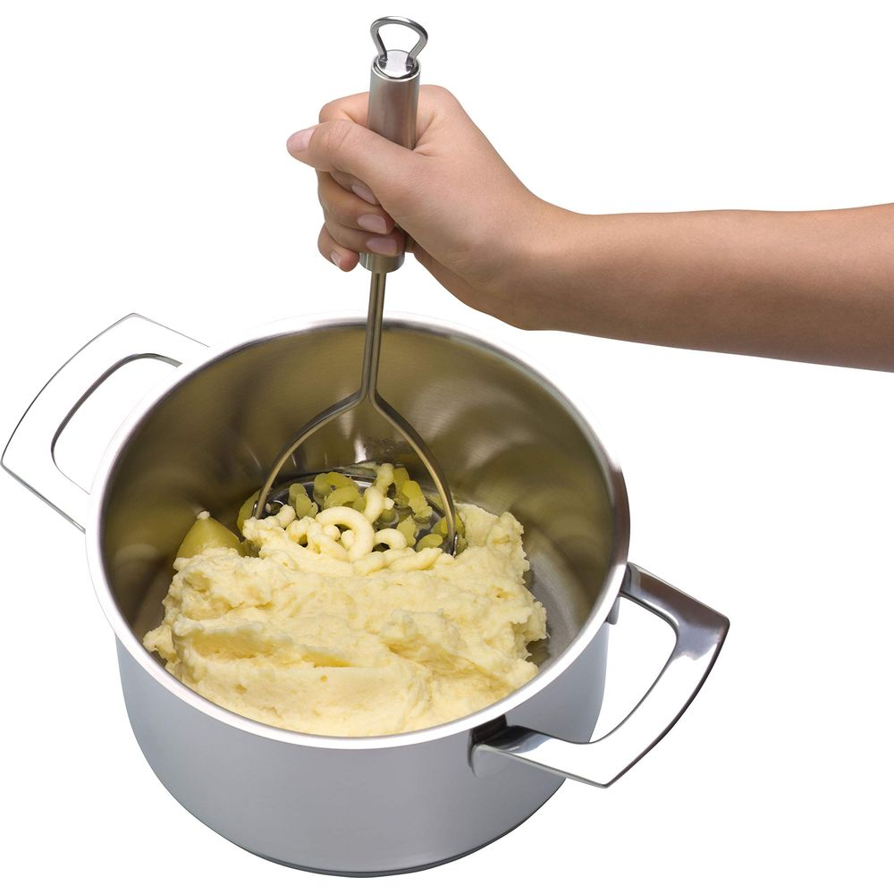 Hand zerdrückt Kartoffeln in einem Topf mit einem Kartoffelstampfer.