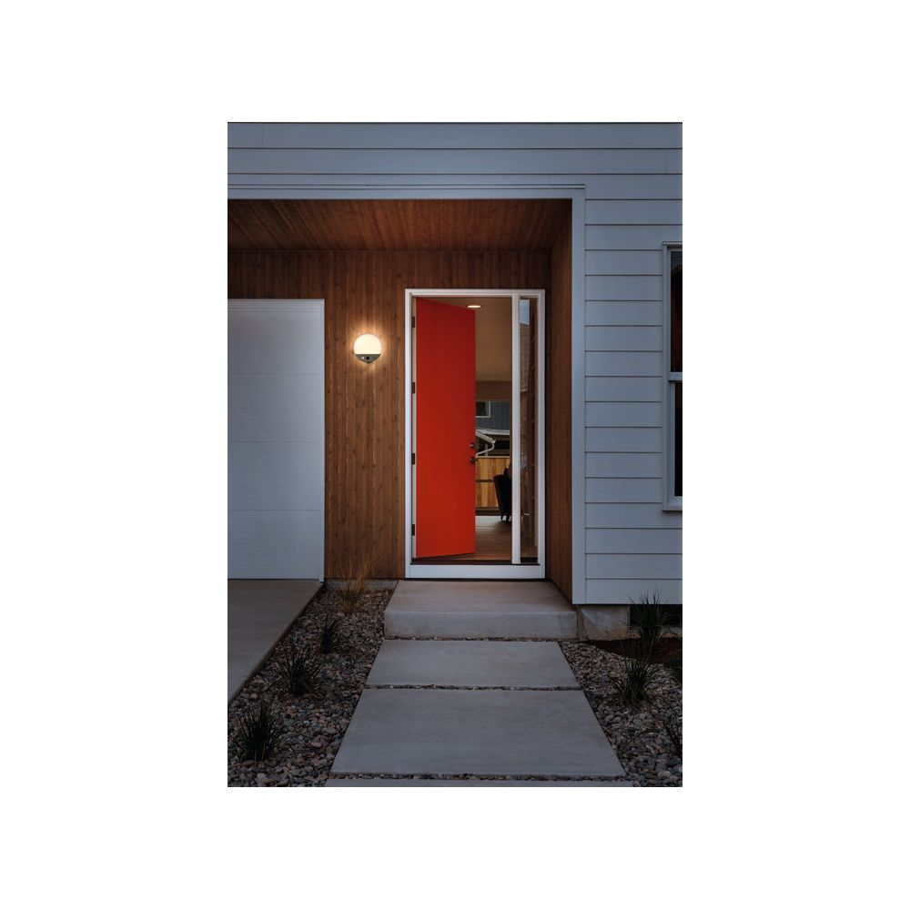 Ein rotes Tor und ein Weg führen zu einem Haus mit Holzverkleidung.
