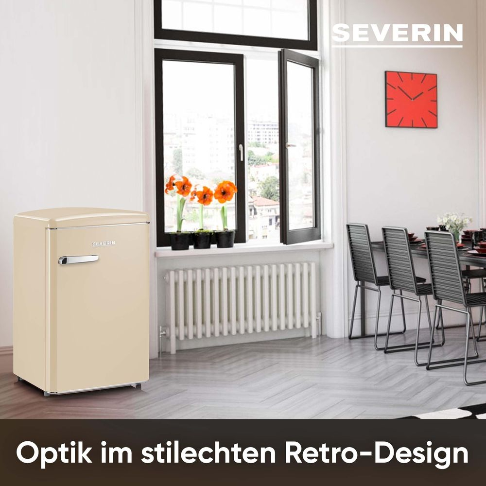Een crème retro koelkast naast een raam met bloemen.
