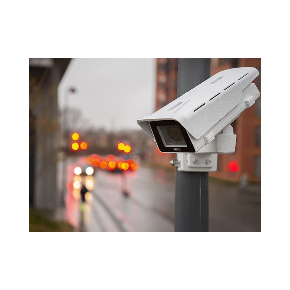 Biała kamera bezpieczeństwa zamontowana na słupie, z rozmytym tłem świateł.