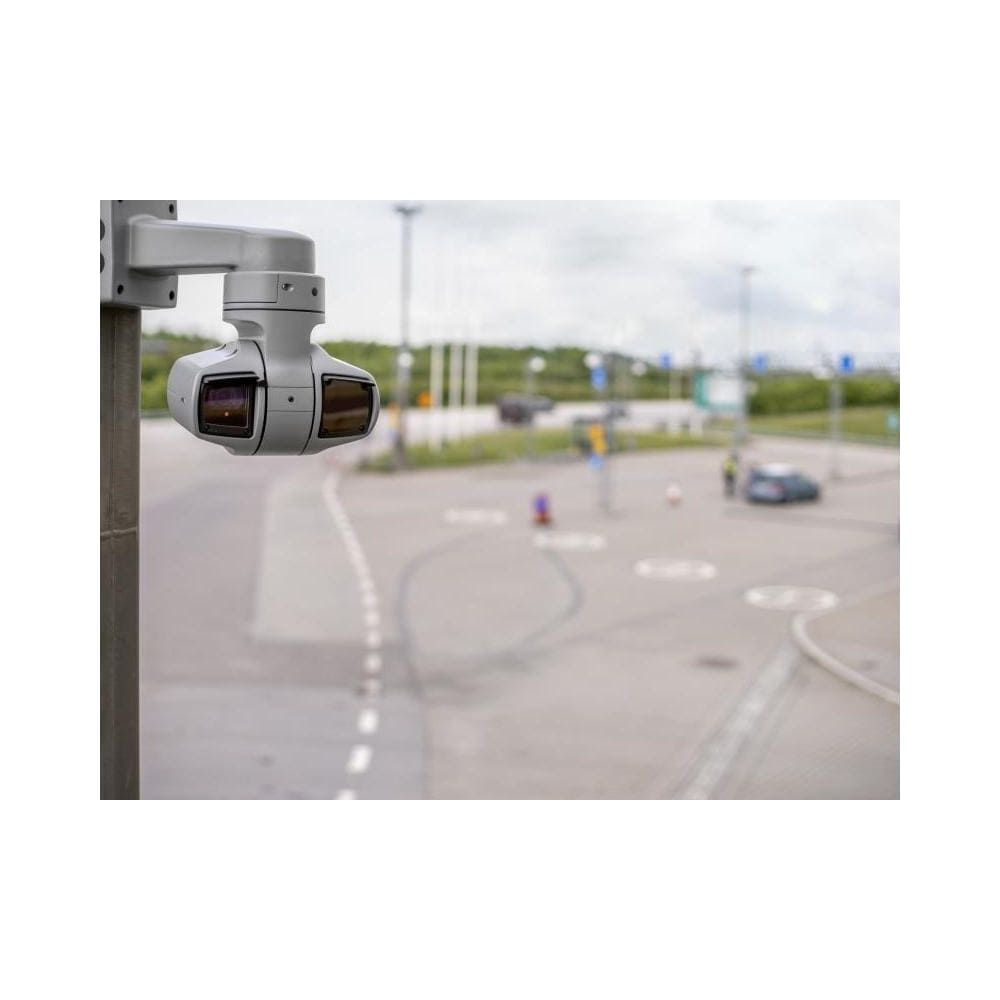 Kamera monitoringu zamontowana na słupie, z rozmytym tłem parkingu.