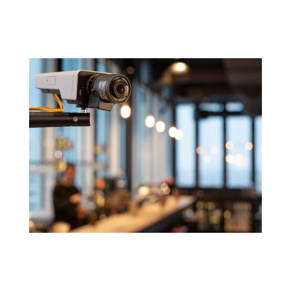 Kamera bezpieczeństwa wisi nad barem. W tle widać światła i okna.