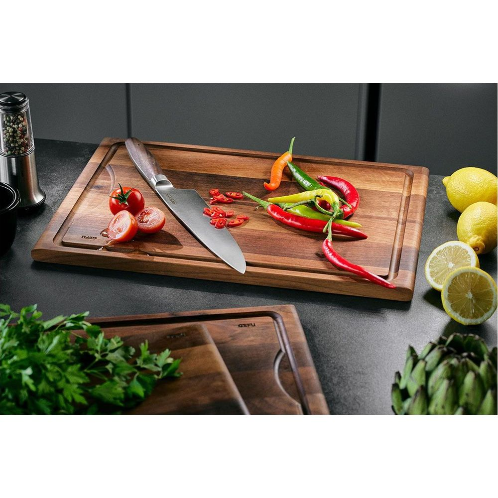 Holzschneidebretter mit Messer, Tomaten, Chilis, Zitronen und Kräutern.