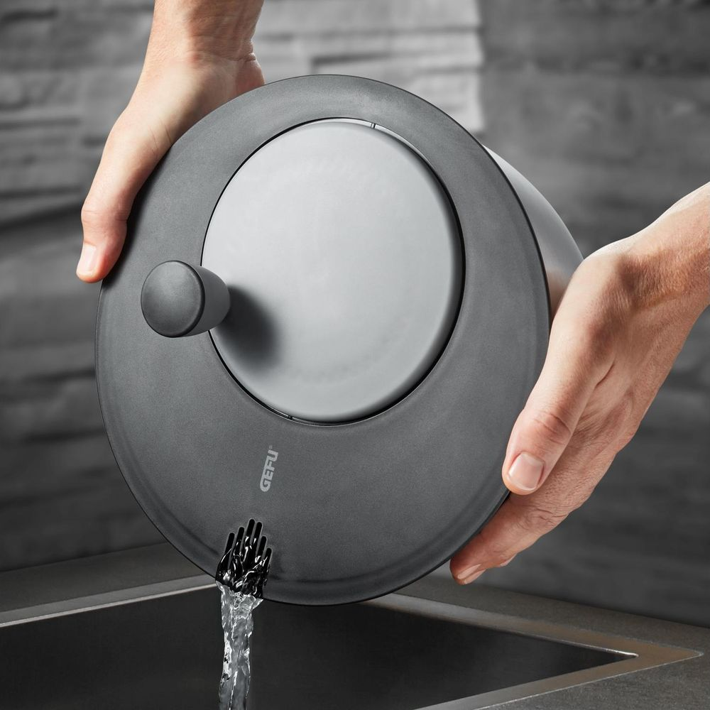 Woda płynie z szarego naczynia z uchwytem do zlewu.