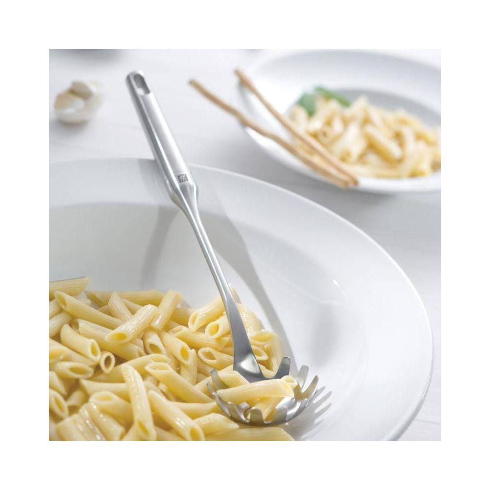 Arka planda başka bir kase bulunan penne makarna kasesinde bir makarna servis kaşığı.