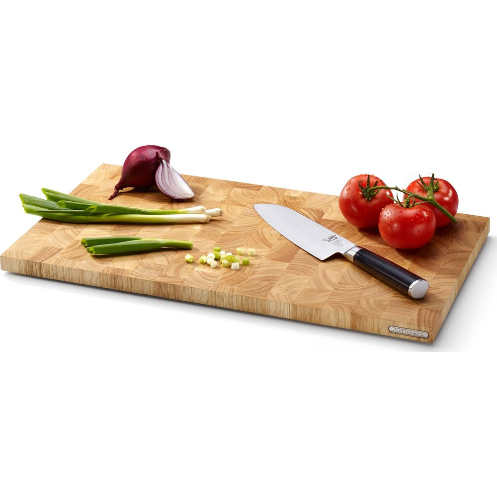 Ein Messer liegt auf einem Holzbrett neben Tomaten, Zwiebeln und Frühlingszwiebeln.