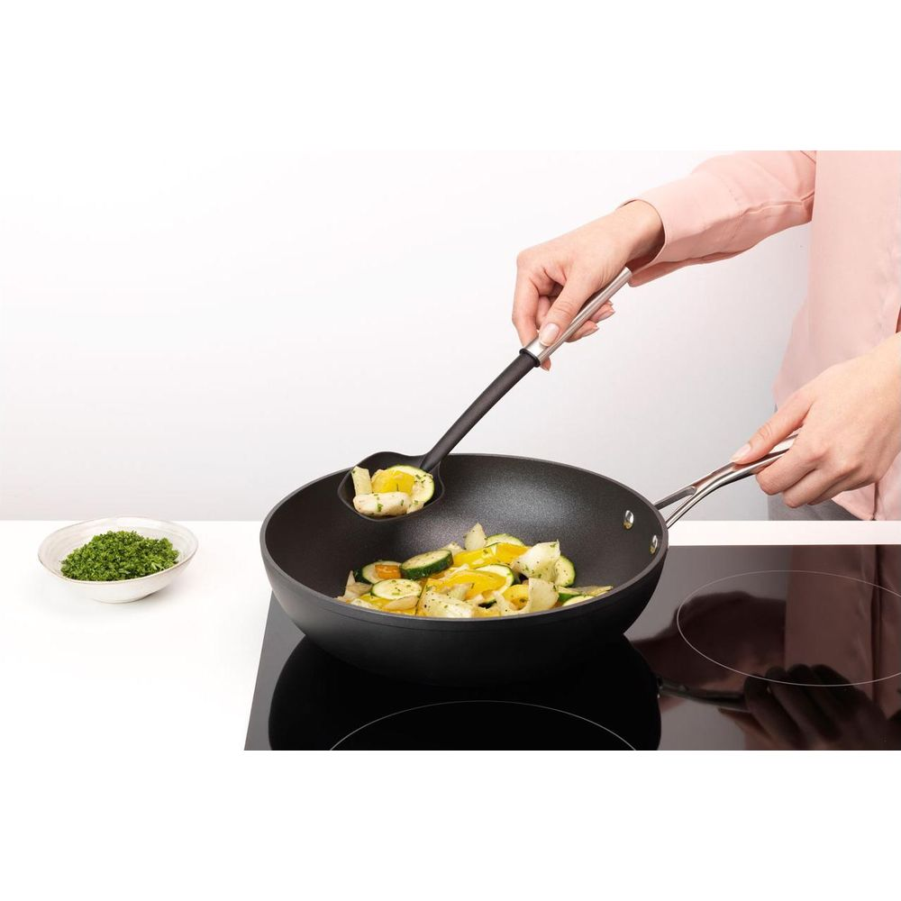 Verdure cotte in una padella wok su un piano cottura.