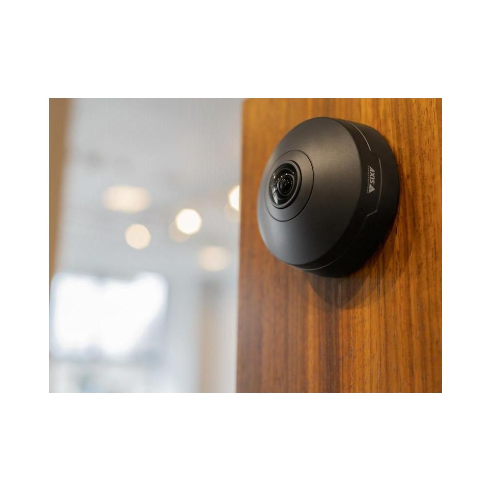 Czarna kamera bezpieczeństwa zamontowana na drewnianej ścianie.