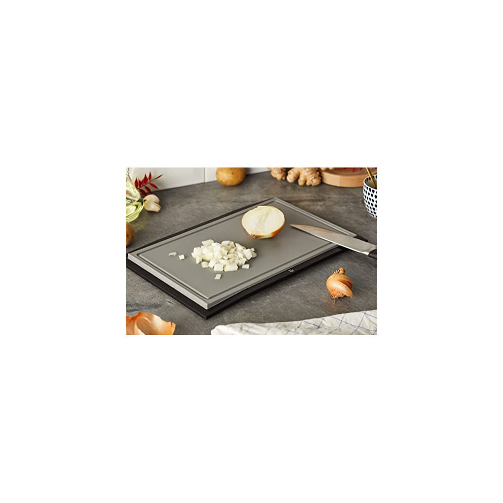 Un oignon haché sur une planche à découper à côté d'un demi-oignon et d'un couteau.