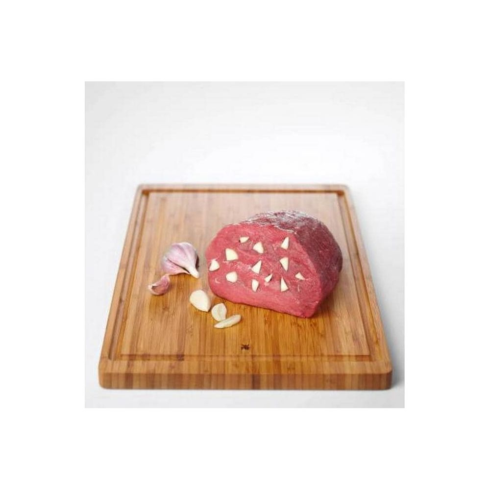 Rohes Rindfleisch mit Knoblauchspitzen auf einem Holzbrett.