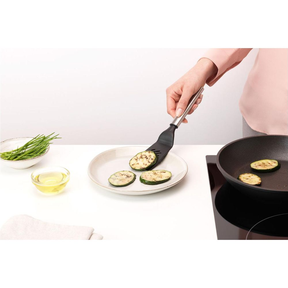 Fette di zucchine vengono messe su un piatto con una spatola.