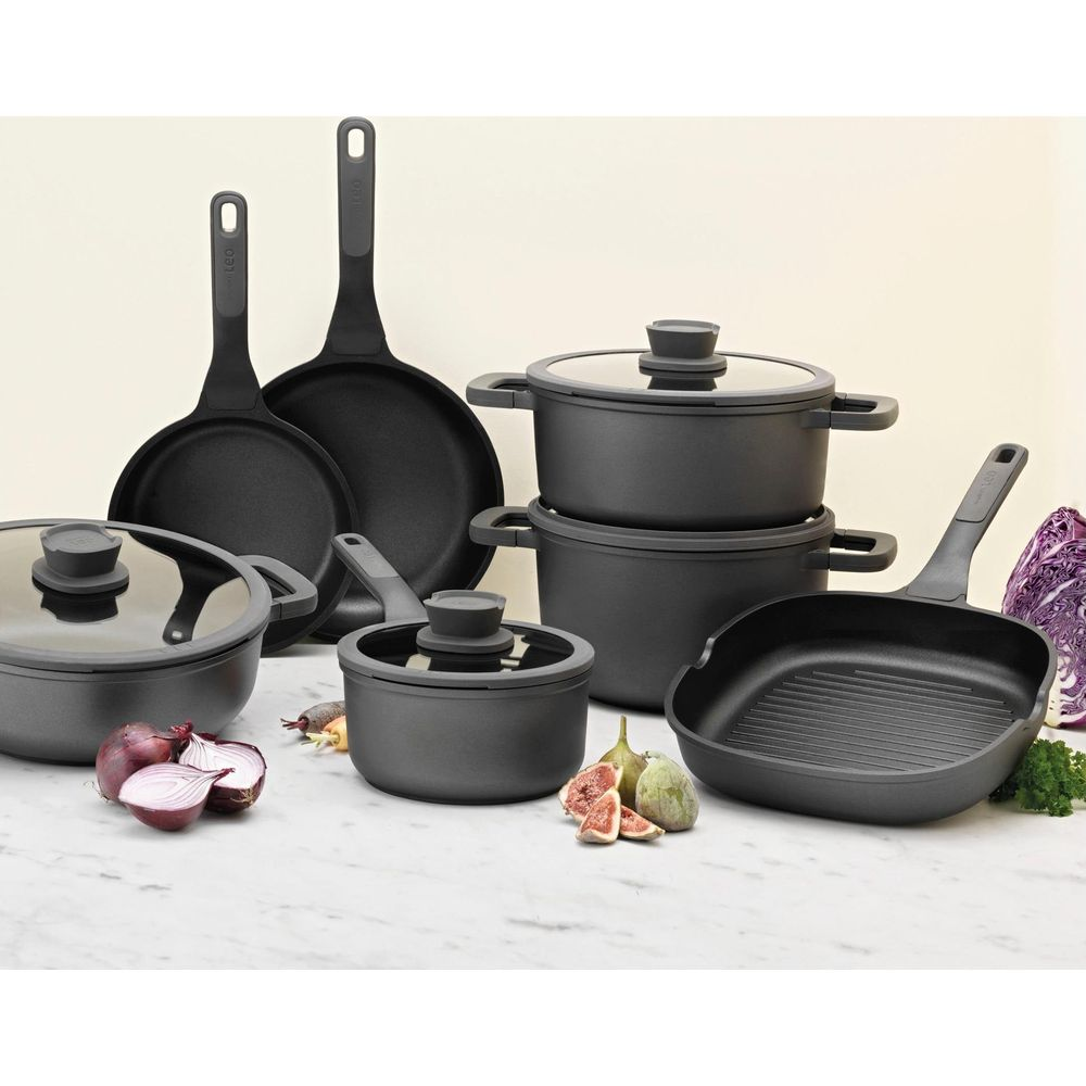 Kookgerei set met potten, pannen en grillpan, gegarneerd met uien, vijgen en kool.