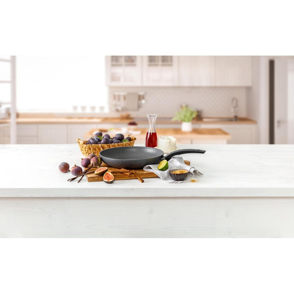 Poêle avec fruits et ingrédients sur planche en bois dans une cuisine.
