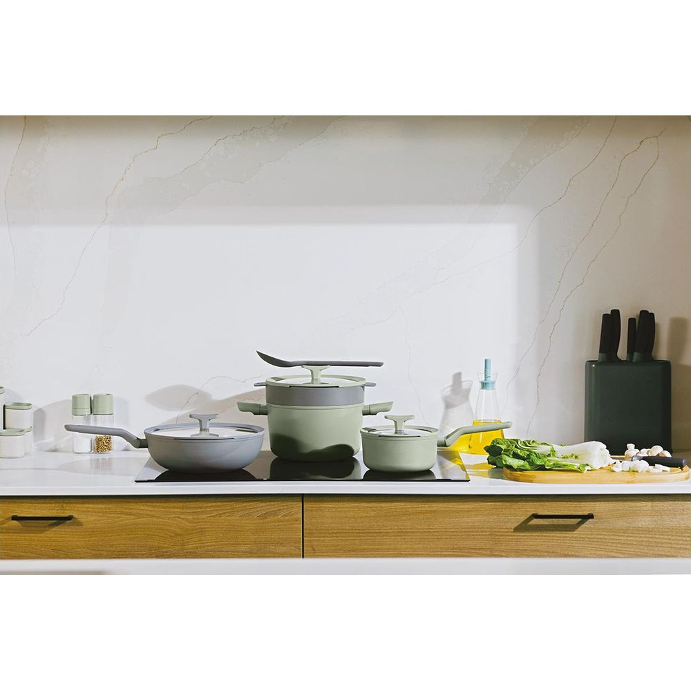 Groene kookgerei set met lepel, pan, pot, oliefles en groenten.