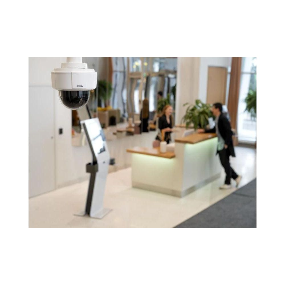 Kamera bezpieczeństwa wisi nad recepcją z kioskiem i dwiema osobami.