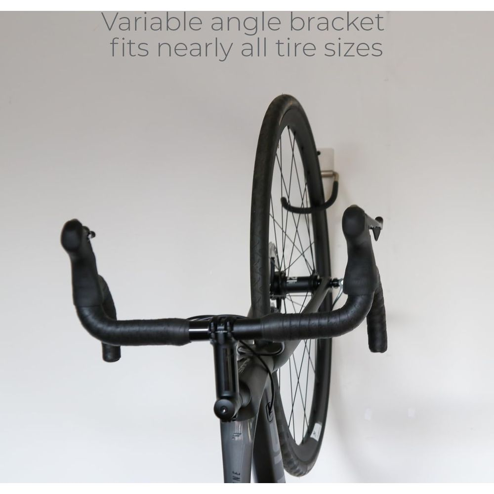 Szary rower wiszący pionowo na uchwycie ściennym. Kierownica i przednie koło w centrum uwagi.