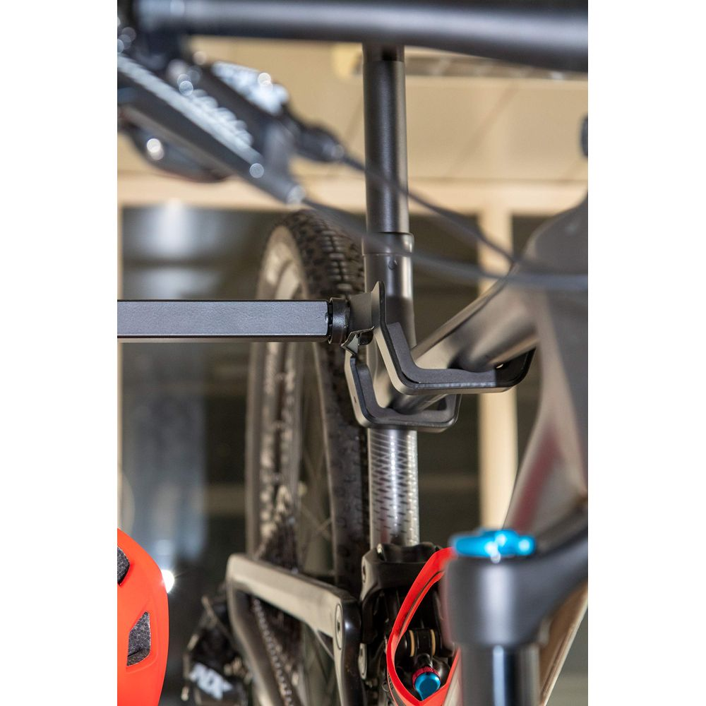 Zbliżenie ramy roweru ze amortyzatorem i oponą. Widoczny czerwony kask.