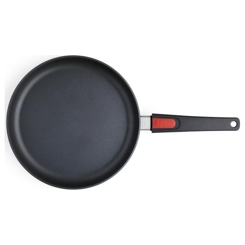Eine schwarze Pfanne mit rotem Griff, von oben gesehen.
